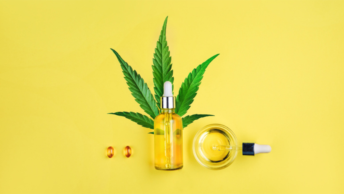 CBD oil and CBD capsules with hemp leaf in yellow background