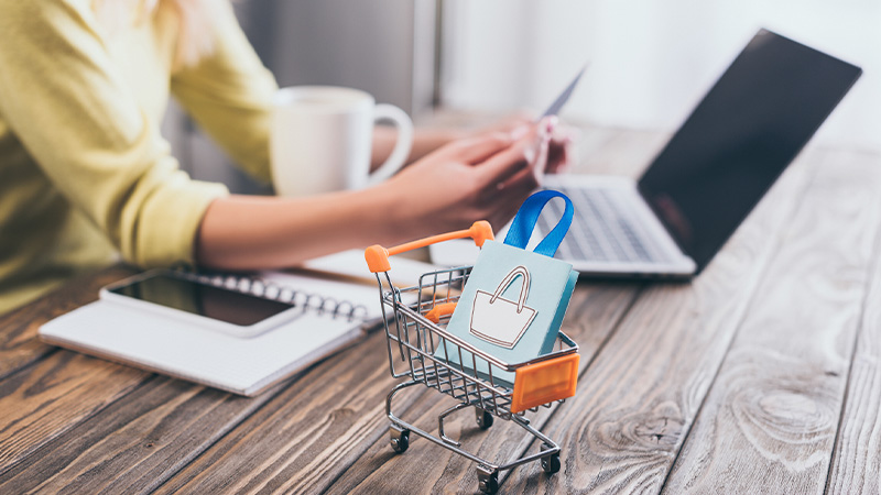 Selective focus on shopping cart with shopping bag and a woman on the background